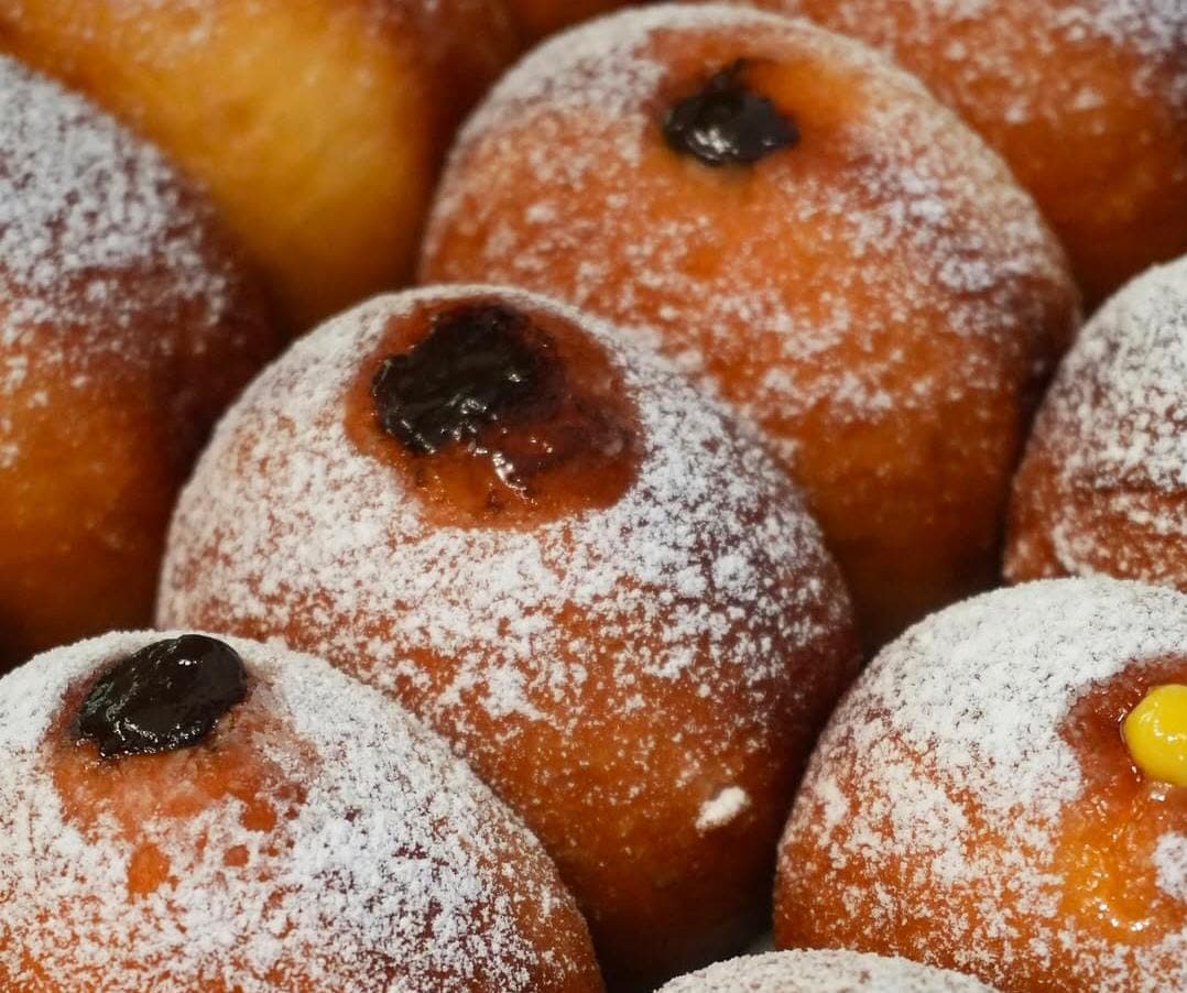 Bomboloni dusted with sugar, filled with Nutella and custard.